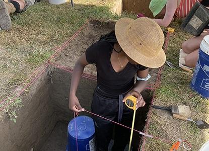 Field Archaeology student measuring excavation site at 365足彩外围's Pine Lake Environmental Campus dig